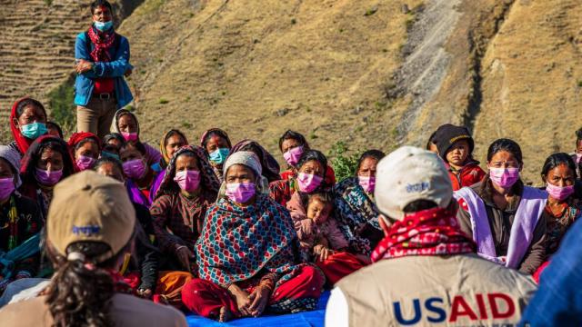 A group of people sitting and listening to USAID staff. Credit: USAID Nepal